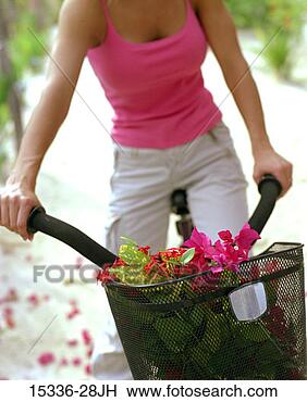 Stock Photo - woman riding bicycle 
with basket full 
of flowers, belize. 
fotosearch - search 
stock photos, 
pictures, images, 
and photo clipart