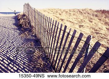 Stock Photo - woman walking 
beside a wooden 
beach fence, popham 
beach, maine, 
usa. fotosearch 
- search stock 
photos, pictures, 
images, and photo 
clipart