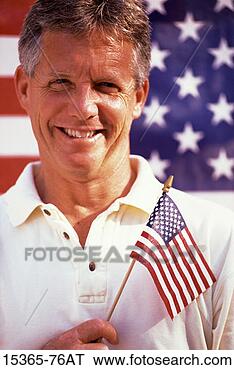 Stock Photo - middle-aged man 
holding small 
american flag, 
standing in front 
of flag. fotosearch 
- search stock 
photos, pictures, 
images, and photo 
clipart