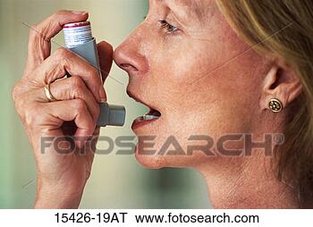 Stock Photo - woman holding 
inhaler to her 
mouth for asthma 
relief. fotosearch 
- search stock 
photos, pictures, 
images, and photo 
clipart