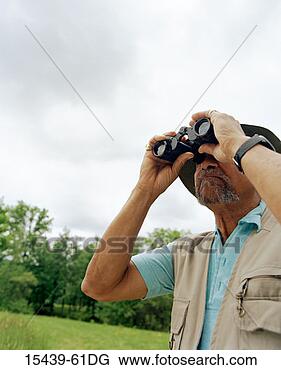 Stock Photo - mature man with 
binoculars, bird 
watching in field. 
fotosearch - search 
stock photos, 
pictures, images, 
and photo clipart