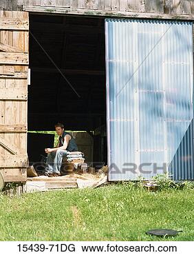 Stock Photo - young man sitting 
in doorway of 
barn. fotosearch 
- search stock 
photos, pictures, 
images, and photo 
clipart
