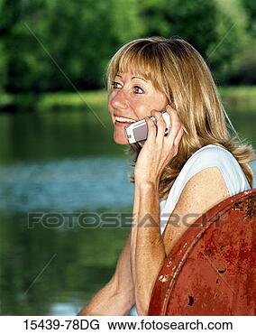 Stock Photo - young woman on 
cellphone, sitting 
in chair by pond. 
fotosearch - search 
stock photos, 
pictures, images, 
and photo clipart