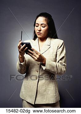 Stock Photo - latina business 
woman, standing, 
looking at pda 
in her hands. 
fotosearch - search 
stock photos, 
pictures, images, 
and photo clipart