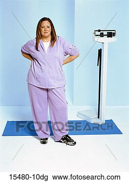 Stock Photo - plus-sized woman 
standing next 
to scale, hands 
on hips. fotosearch 
- search stock 
photos, pictures, 
images, and photo 
clipart