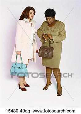 Stock Photo - two plus-sized 
women holding 
purses,  standing, 
 one looking at 
her. fotosearch 
- search stock 
photos, pictures, 
images, and photo 
clipart
