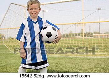 Stock Photo - boy in soccer 
uniform holding 
soccerball by 
goal. fotosearch 
- search stock 
photos, pictures, 
images, and photo 
clipart