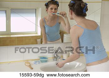 Stock Photo - woman brushing 
her teeth and 
looking in bathroom 
mirror. fotosearch 
- search stock 
photos, pictures, 
images, and photo 
clipart