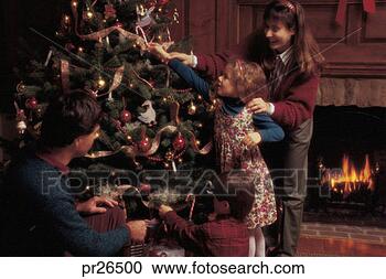 Stock Photography - family hanging 
ornaments on christmas 
tree. fotosearch 
- search stock 
photos, pictures, 
images, and photo 
clipart