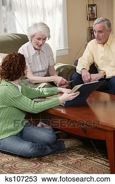 Stock Photo - parents and grown 
daughter looking 
at photo album 
together. fotosearch 
- search stock 
photos, pictures, 
images, and photo 
clipart