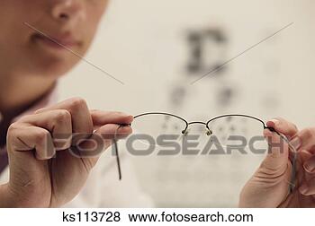 Stock Photo - person holding 
eyeglasses, eye 
chart in background. 
fotosearch - search 
stock photos, 
pictures, images, 
and photo clipart