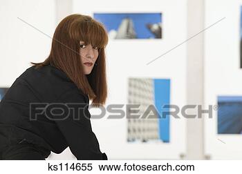 Stock Image - portrait of a 
woman, photographs 
hanging in background. 
fotosearch - search 
stock photos, 
pictures, images, 
and photo clipart