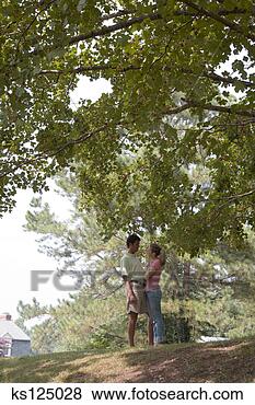 Stock Photo - man and woman 
standing beneath 
verdant tree branches. 
fotosearch - search 
stock photos, 
pictures, images, 
and photo clipart