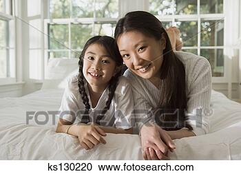 Stock Photography - mother and daughter 
lying down on 
a bed. fotosearch 
- search stock 
photos, pictures, 
images, and photo 
clipart
