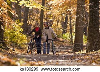 Stock Photograph - couple walking 
their bikes during 
autumn. fotosearch 
- search stock 
photos, pictures, 
images, and photo 
clipart