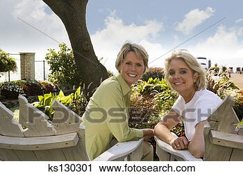 Stock Photography - two woman sitting 
together outdoors. 
fotosearch - search 
stock photos, 
pictures, images, 
and photo clipart