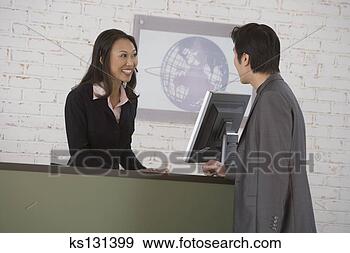 Stock Photograph - businessman talking 
to businesswoman 
behind receptionist 
desk. fotosearch 
- search stock 
photos, pictures, 
images, and photo 
clipart