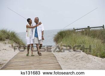 Stock Photo - loving couple 
walking along 
beach path. fotosearch 
- search stock 
photos, pictures, 
images, and photo 
clipart