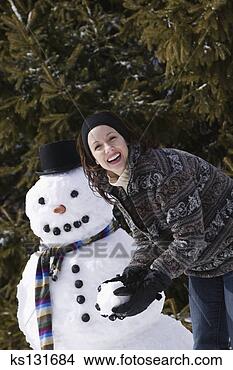 Stock Photo - smiling woman 
with snowball 
next to snowman. 
fotosearch - search 
stock photos, 
pictures, images, 
and photo clipart