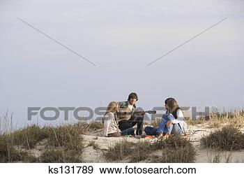 Stock Photograph - teen playing guitar 
on beach with 
friends. fotosearch 
- search stock 
photos, pictures, 
images, and photo 
clipart