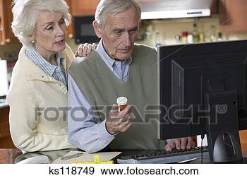 Stock Photograph - elderly couple 
using computer 
and holding prescription. 
fotosearch - search 
stock photos, 
pictures, images, 
and photo clipart