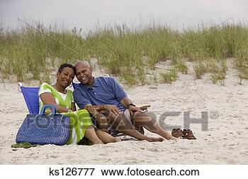 Foto - par,  praia,  
sentando,  junto. 
fotosearch - busca 
de fotos, imagens 
e clipart