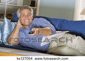 Stock Photo - man with remote 
control reclining 
on couch. fotosearch 
- search stock 
photos, pictures, 
images, and photo 
clipart