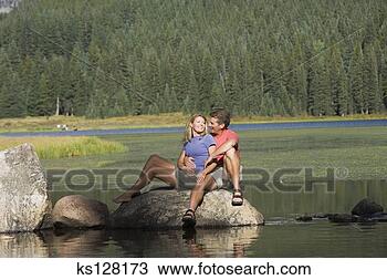 Banco de Imagem - par,  sentando, 
 rocha,  lago. 
fotosearch - busca 
de fotos, imagens 
e clipart