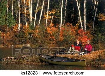 Stock Photography - couple sitting 
by lake with canoe. 
fotosearch - search 
stock photos, 
pictures, images, 
and photo clipart
