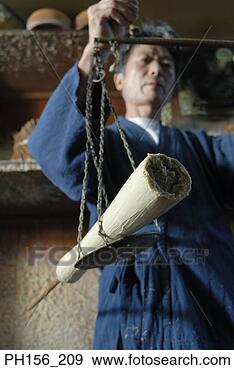 Stock Photograph - low angle view 
of a mid adult 
man weighing a 
candle on a weighing. 
fotosearch - search 
stock photos, 
pictures, images, 
and photo clipart