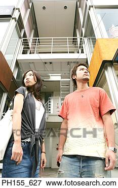 Picture - low angle view 
of a young couple 
standing in front 
of an apartment. 
fotosearch - search 
stock photos, 
pictures, images, 
and photo clipart