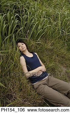 Stock Photo - high angle view 
of a young woman 
lying on the grass. 
fotosearch - search 
stock photos, 
pictures, images, 
and photo clipart