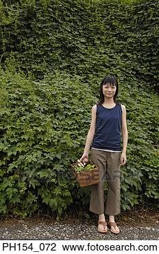 Stock Photo - portrait of a 
young woman holding 
a basket and standing 
in a garden. fotosearch 
- search stock 
photos, pictures, 
images, and photo 
clipart