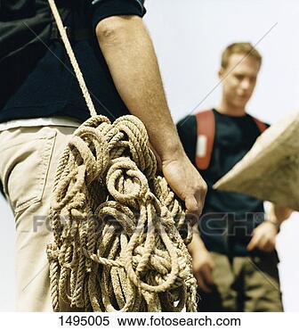 Stock Image - close-up of a 
man with a bundle 
of rope and other 
men reading a 
map. fotosearch 
- search stock 
photos, pictures, 
images, and photo 
clipart