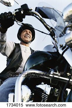 Stock Image - low angle shot 
of a senior male 
biker sitting 
on a motorbike. 
fotosearch - search 
stock photos, 
pictures, images, 
and photo clipart