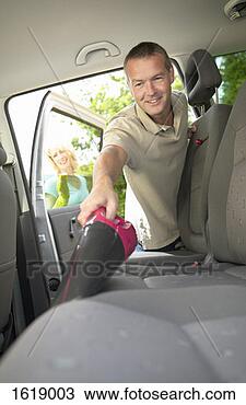 Stock Photo - man using a vacuum 
cleaner to clean 
car seats,  while 
a woman cleans. 
fotosearch - search 
stock photos, 
pictures, images, 
and photo clipart