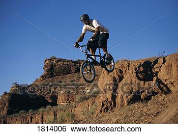 Stock Photo - mid-air shot of 
a man riding a 
bike off a rock 
on the plains. 
fotosearch - search 
stock photos, 
pictures, images, 
and photo clipart