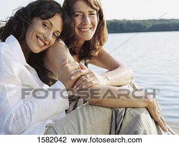 Stock Photo - mother and daughter 
sitting close 
to each others 
at water's edge. 
fotosearch - search 
stock photos, 
pictures, images, 
and photo clipart