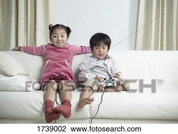 Stock Photo - satisfied girl 
sitting next to 
her brother holding 
a games controller. 
fotosearch - search 
stock photos, 
pictures, images, 
and photo clipart