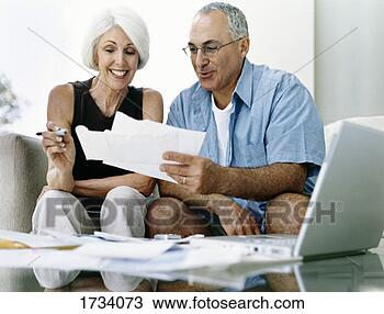 Stock Photo - senior couple 
sitting on a sofa 
examining their 
invoices. fotosearch 
- search stock 
photos, pictures, 
images, and photo 
clipart