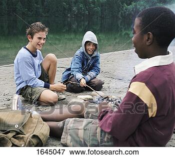 Picture - three young boys 
sit on the riverbank 
by a campfire, 
laughing. fotosearch 
- search stock 
photos, pictures, 
images, and photo 
clipart