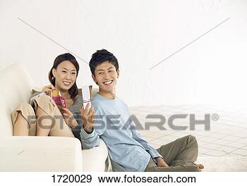 Stock Photograph - woman sits on 
a sofa,  her boyfriend 
sitting on the 
floor taking a. 
fotosearch - search 
stock photos, 
pictures, images, 
and photo clipart