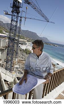 Stock Photo - man sitting on 
a railing holding 
a rolled-up blueprint 
watching a. fotosearch 
- search stock 
photos, pictures, 
images, and photo 
clipart