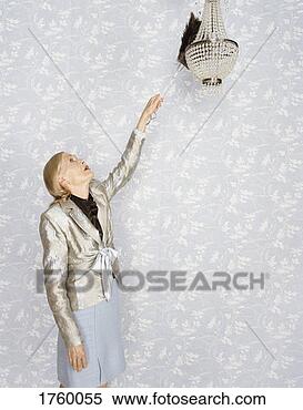Stock Image - senior woman using 
a feather duster 
to clean a chandelier. 
fotosearch - search 
stock photos, 
pictures, images, 
and photo clipart