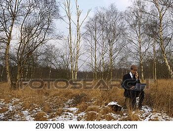 Stock Photo - businessman sitting 
on a tree stump 
and using his 
laptop and mobile. 
fotosearch - search 
stock photos, 
pictures, images, 
and photo clipart