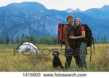 Stock Photo - hiking couple 
standing with 
dog in front of 
moutain range 
and next to. fotosearch 
- search stock 
photos, pictures, 
images, and photo 
clipart