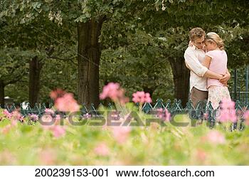 Stock Photography - couple standing 
in park embracing 
(focus on couple). 
fotosearch - search 
stock photos, 
pictures, images, 
and photo clipart