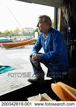 Stock Photography - male boat builder 
looking out of 
workshop, smiling, 
side view. fotosearch 
- search stock 
photos, pictures, 
images, and photo 
clipart