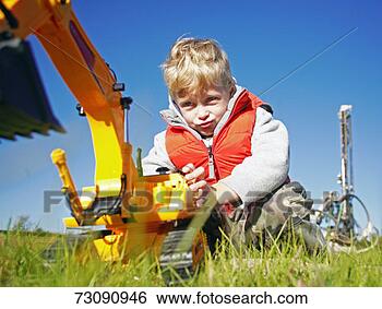 Stock Photo - boy (5-7) playing 
with toy digger 
in grass, low 
angle view. fotosearch 
- search stock 
photos, pictures, 
images, and photo 
clipart