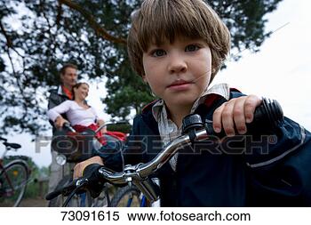 Stock Image - boy (6-7) on bicycleparents 
in backgroundportrait. 
fotosearch - search 
stock photos, 
pictures, images, 
and photo clipart